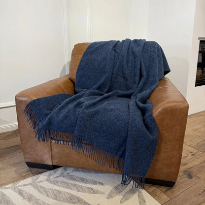 Pătură albastru melanj din lână 100%, plasată pe fotoliu elegant