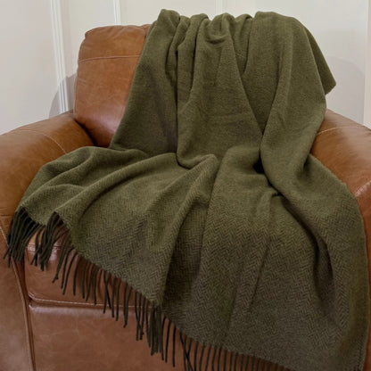 Pătură verde kaki din lână 100%, plasată elegant pe fotoliu din piele