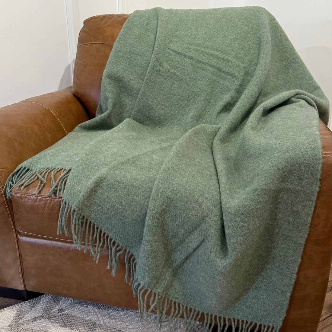 Pătură verde caldă din lână, așezată într-un decor cozy