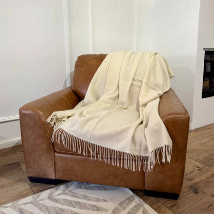 Pătură albă MERINO 140x200 cm, din lână merino moale și elegantă, întinsă pe fotoliu
