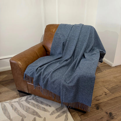 Pătură albastră din lână merinos așezată elegant pe fotoliu maro