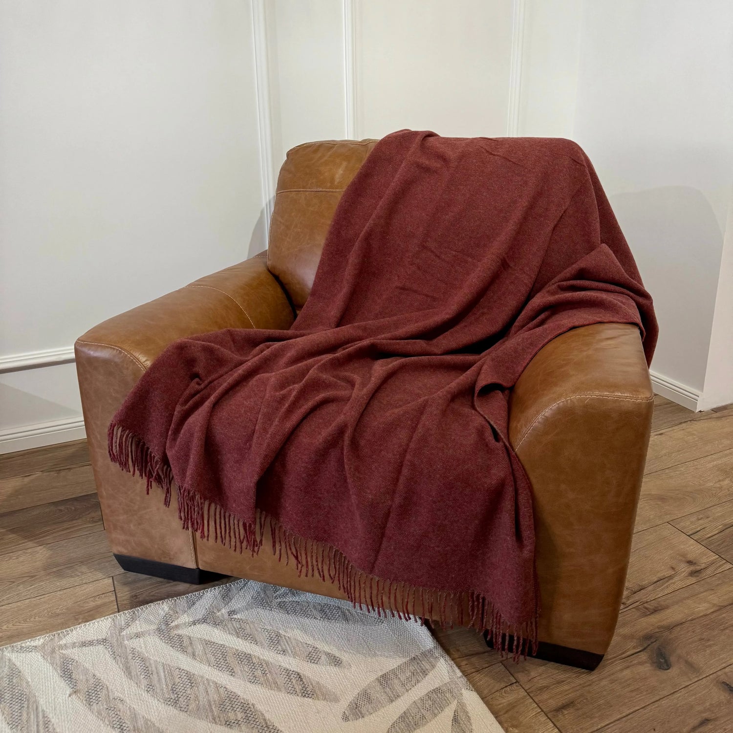 Pătură vișiniu închis elegantă, plasată pe fotoliu din piele