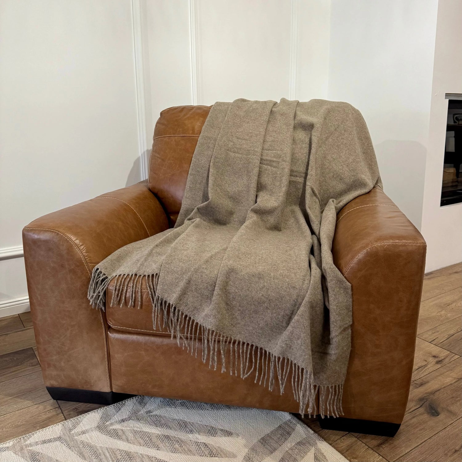 Pătură maro deschis din lână Merino pe fotoliu din piele
