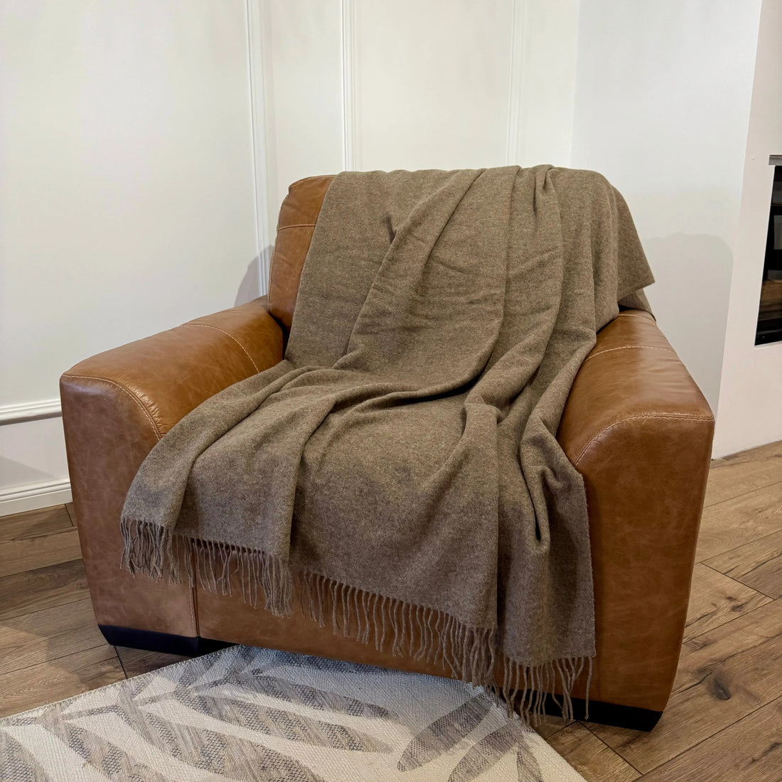 • Pătură maro deschis din lână merino, expusă pe fotoliu din piele
