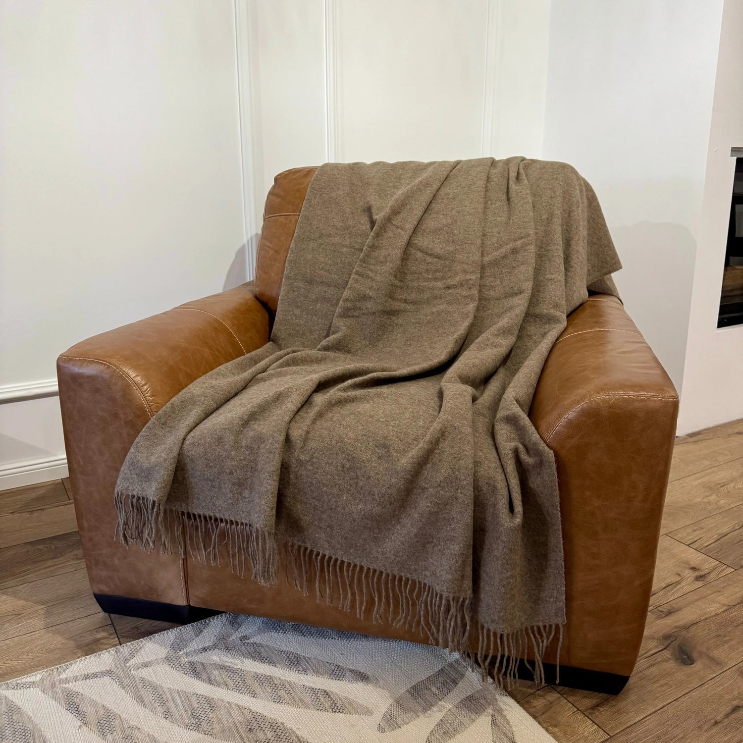 • Pătură maro deschis din lână merino, expusă pe fotoliu din piele
