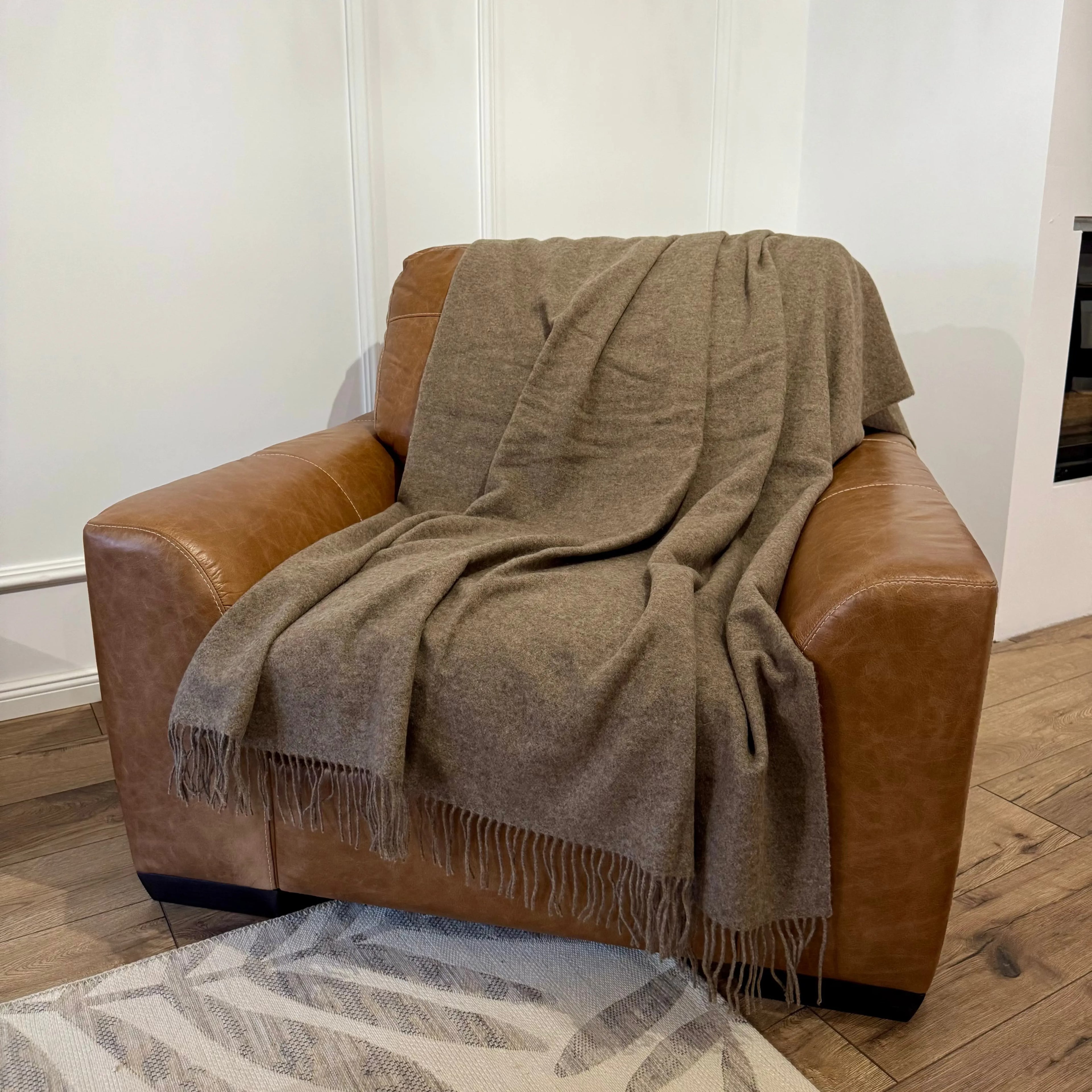 • Pătură maro deschis din lână merino, expusă pe fotoliu din piele
